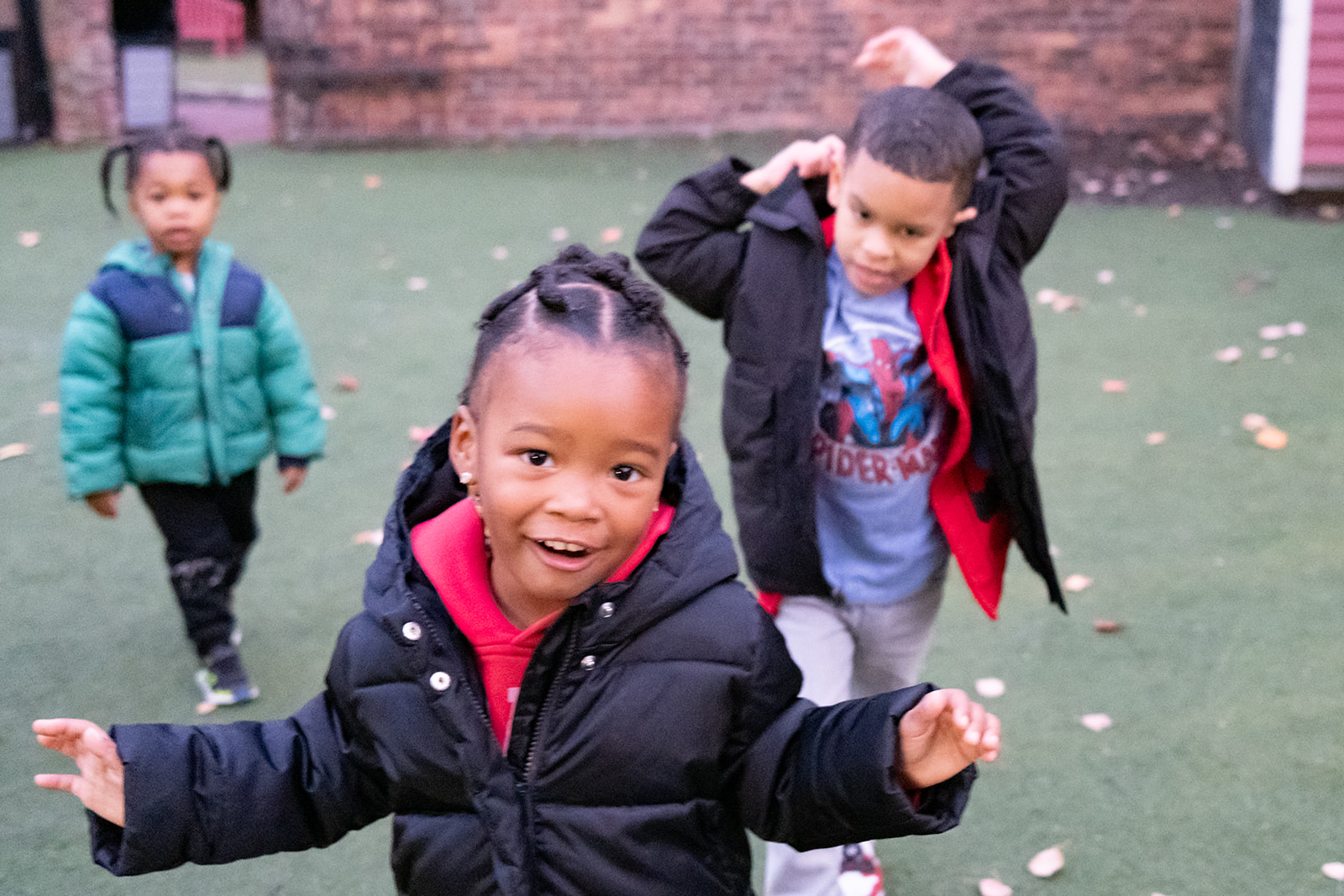 Three children in the USES Early Childhood Education program are playing outside