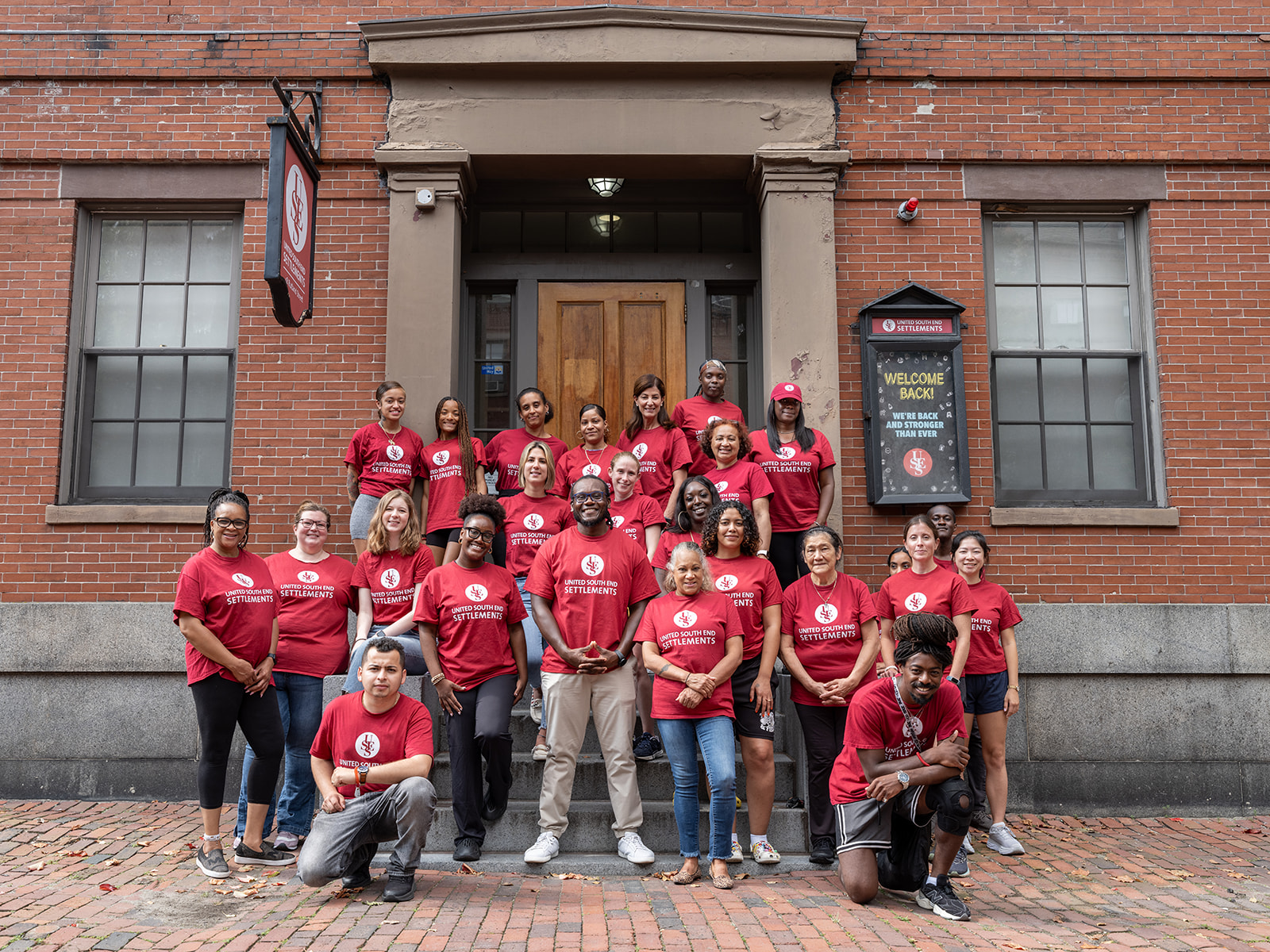 All USES staff in their red USES tshirts posing on the front steps of the building.